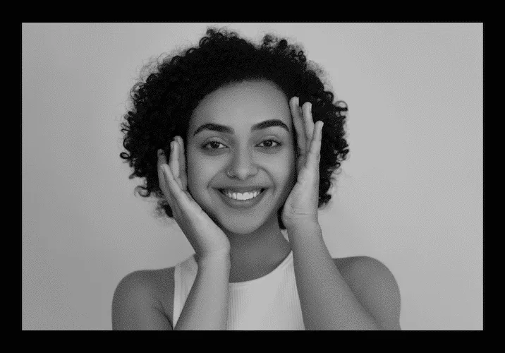 A woman smiling, hands framing her face